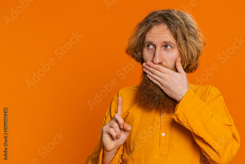 I will not say anything. Frightened bearded man closing mouth with hands, looking intimidated scared at camera gestures no refusing to tell terrible secret unbelievable truth. Guy on orange background photo