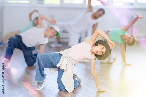 Concetrated preteen boys and girls studying movement of contemporary dance in classroom with his friends photo