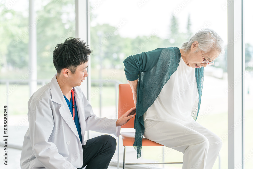 Obraz premium 男性医師に腰痛を訴えるシニア女性 