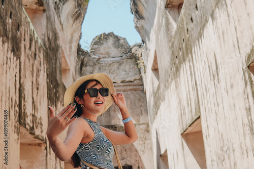 Smiling young Asian woman doing invite hand gesture inside of Tamansari building ruin, Yogyakarta. photo