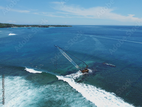 Wall Mural Aerial view of a wrecked ship partially submerged in the clear turquoise ocean near a tropical island