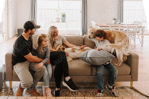 Happy family comfortably sitting on the couch with their dogs in the living room. photo