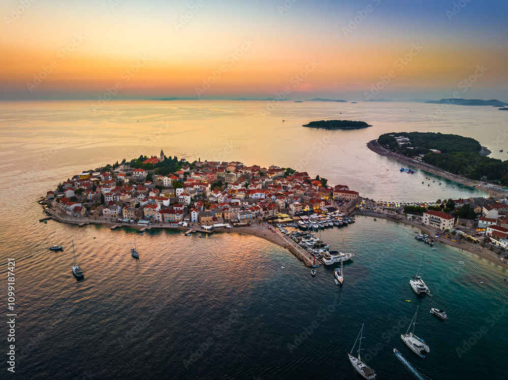 Primosten, Croatia - Aerial view of Primosten peninsula and old town on a sunny summer morning in Dalmatia, Croatia with yachts, blue and golden sky at sunrise on the Adriatic sea coast