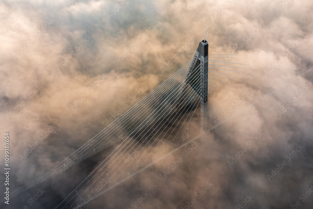 Budapest, Hungary - Aerial view of Megyeri Bridge over River Danube on a foggy autumn afternoon with golden coloured fog bellow