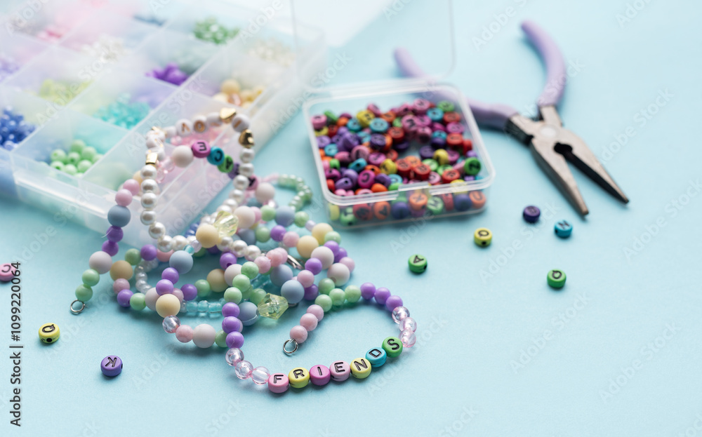 Colorful beads and pliers creating friendship bracelets on blue background