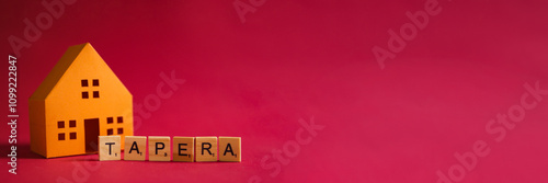 A small orange paper house model next to the word 