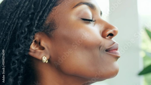 Wallpaper Mural Close-up video of a middle-aged black woman with locs, expressing serenity in natural window light. Torontodigital.ca