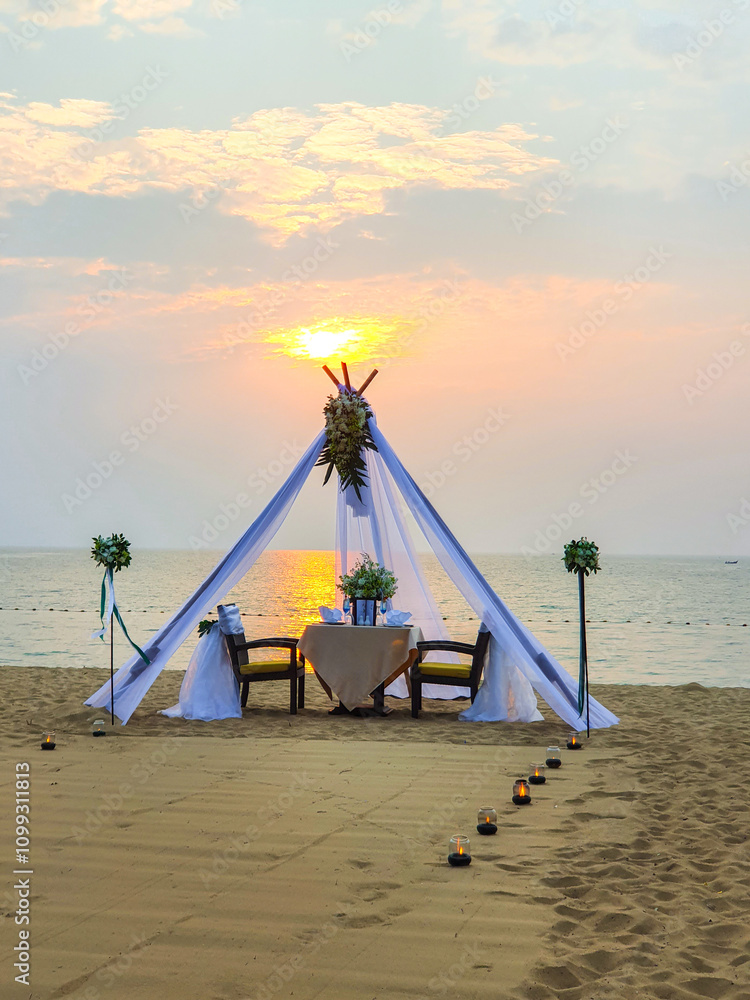 Fototapeta premium An intimate beachside dinner set up under a beautiful sunset at a serene seaside location in Pattaya
