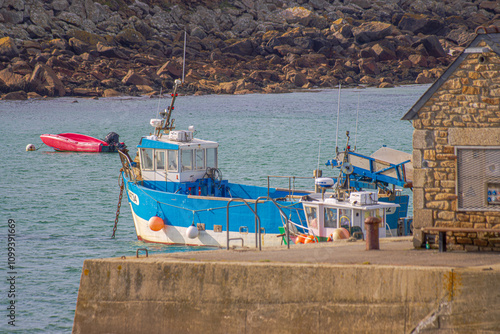 Colorful fishing boats rest in a serene harbor in Brittany, their hulls reflecting in the calm water. Surrounded by rugged coasts and quaint villages, the scene exudes maritime charm and tradition.