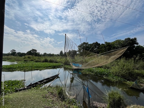 Fishing net in the pond with a boat and Clouds in the sky in Majuli island Assam photo