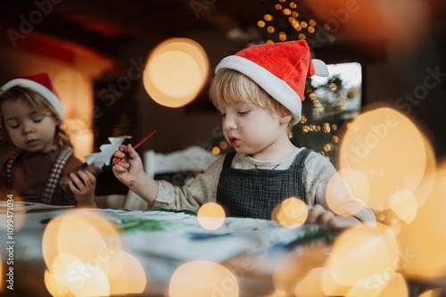 Siblings making holiday Christmas cards for family. Children painting pictures for Santa Claus or making christmas decorations with tempera paints. photo