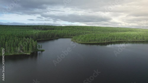 Discover the serene beauty of Lake Västra Rotsjön as the drone glides over lush forests and tranquil water. Experience the pristine landscape of Storsjö Jämtland Sweden. Aerial shot sideways movement photo