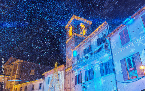 View of the main square of Mombaroccio medieval village during winter snowfall in the Marche region, Italy