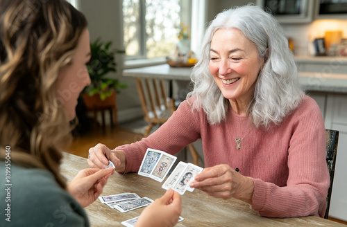 A grandmotherly figure with silver hair and a warm smile, reading tarot cards for a younger woman in a sunny, plant-filled kitchen photo