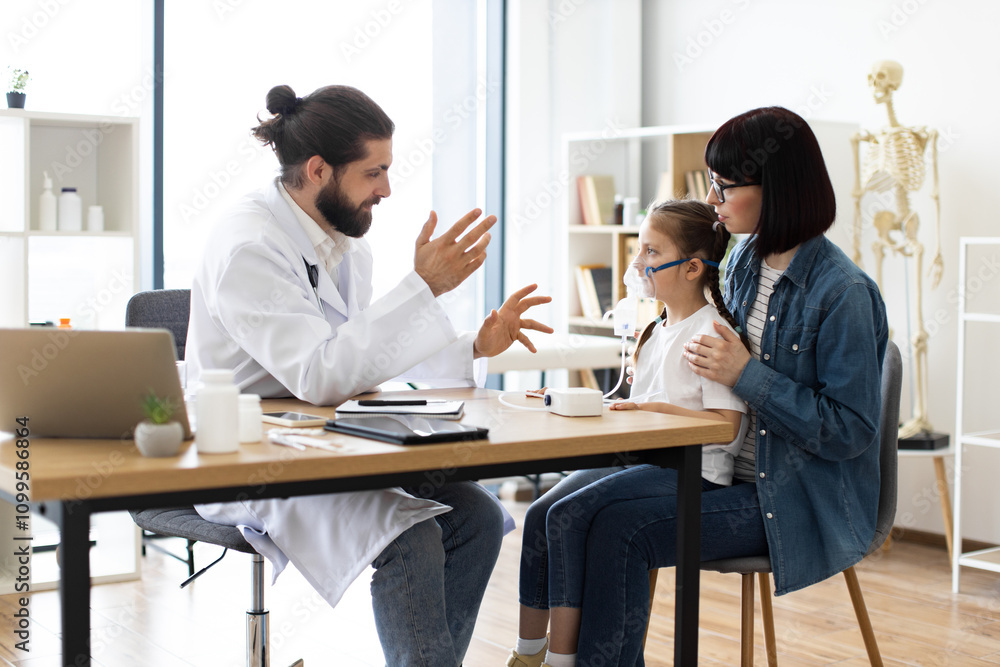 Obraz premium Caucasian male doctor assists young Caucasian girl with inhalation therapy while mother observes at clinic. Warm and caring interaction highlights importance of healthcare and family support.