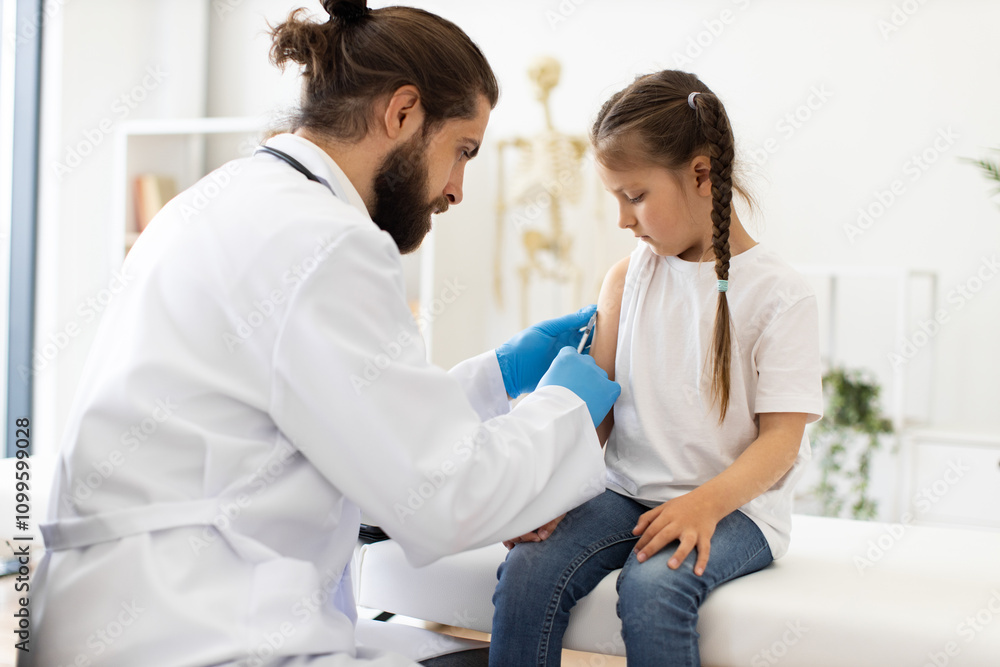 Obraz premium Male doctor vaccinates young Caucasian girl on medical couch with syringe. Doctor wears white coat, gloves, and focuses on girl's arm. Scene depicts healthcare, medical care, and vaccination process.