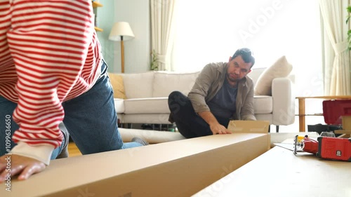 Happy Couple Assembles Furniture as a Team, Girl Reads Instructions and Boy Tightens Screw with a Drill. Moving into New Apartment, Couple Assemble Shelf.