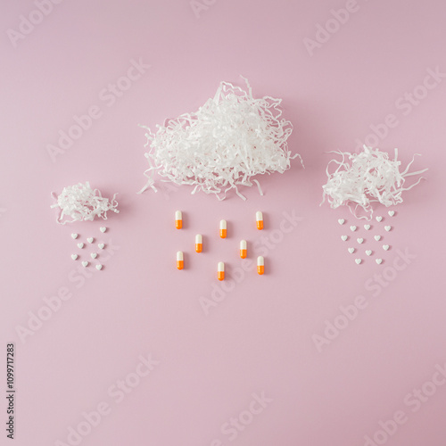 Creative arrangement of pills and shreds resembling clouds and rain on pink background