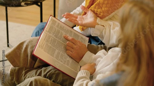Mom reading the Nativity story in the Bible to her children at Christmas eve. Family time at Christmas. Family traditions. Story time.