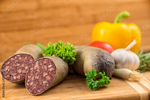 Angeschnittene Blutwurst und ganze Rotwurst garniert mit Petersilie vor einem Holz Hintergrund photo