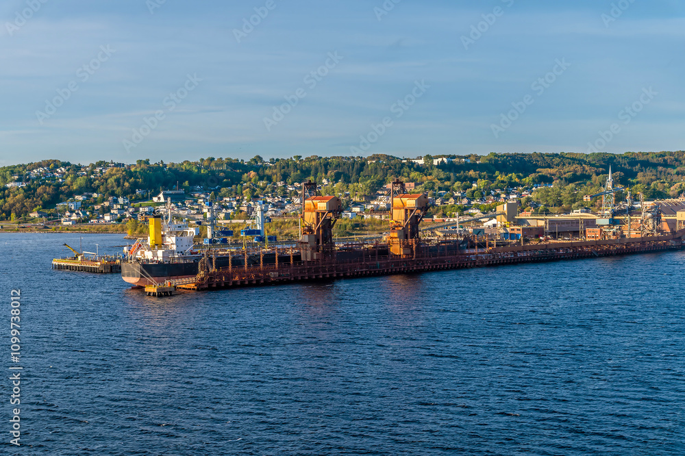 Naklejka premium A view from a ship along the side of the industrial port in the bay at Saguenay, Quebec in Canada in the fall