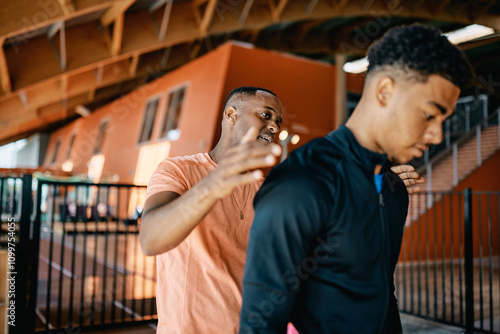 Smiling trainer giving a fit young man a pat on the back after a workout session together at the gym photo