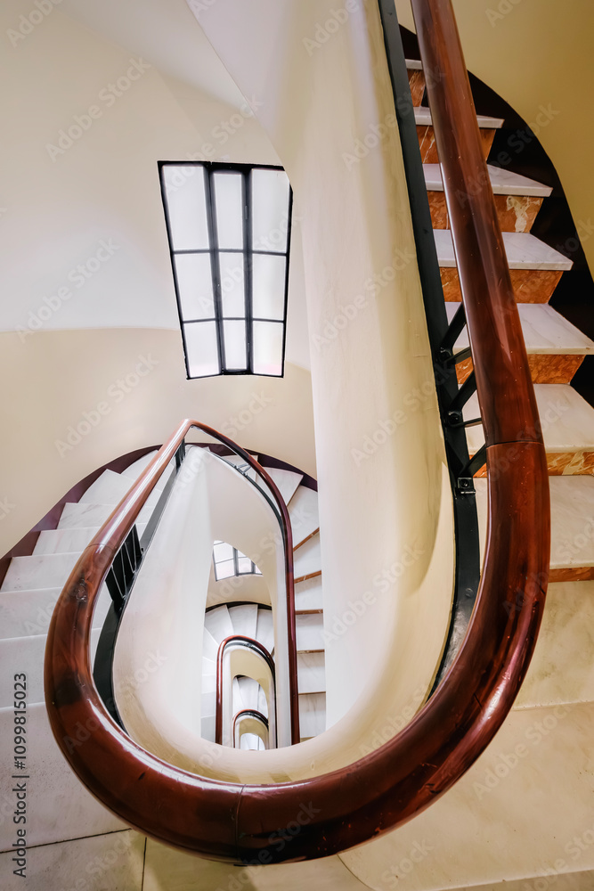 Spiral Staircase In A Residential Building In Barcelona, Spain The Staircase Features A Curved Wooden Handrail And Marble Steps, Leading To A Stylish Home Entrance