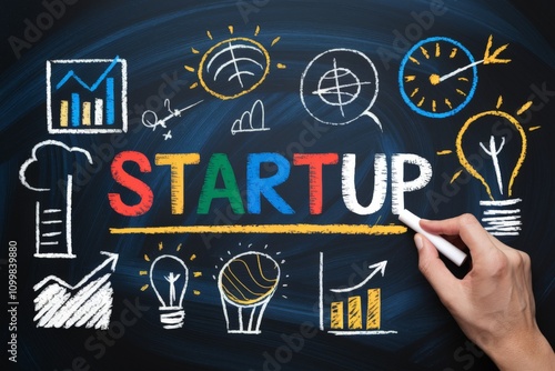 Hand writing the word startup on a blackboard.