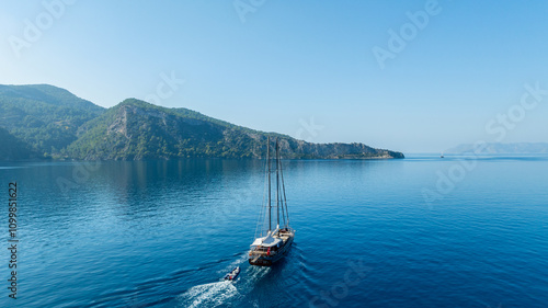 Φωτογραφία A gulet ship anchored near turquoise waters, with green hills in the background, creating a serene and picturesque scene