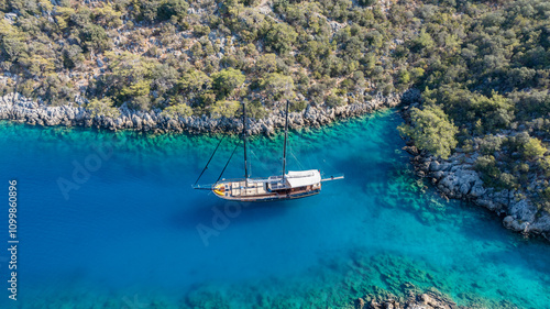 A gulet ship anchored in crystal-clear waters, surrounded by lush green hills and a serene coastal landscape. photo