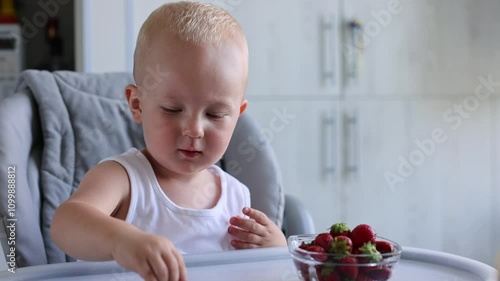 Mother giving to her little child plate with strawberries and happy kid eating berries. 4K