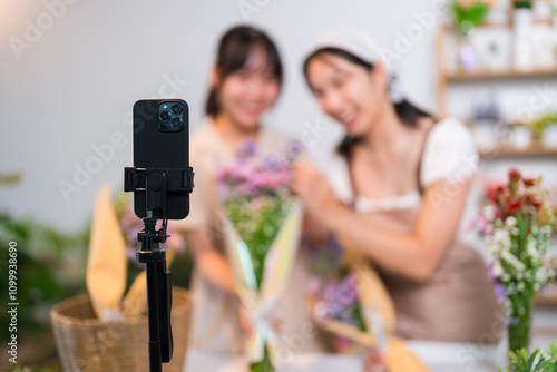 Two florists live-streaming flower sales, showcasing vibrant bouquets and engaging with an online audience in a cozy flower shop photo