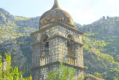 Fotografia Architecture in the Old Town of Kotor: a bell tower with arched windows and an onion dome against the backdrop of a mountain with the Church of Our Lady of Health and the Fortress of St