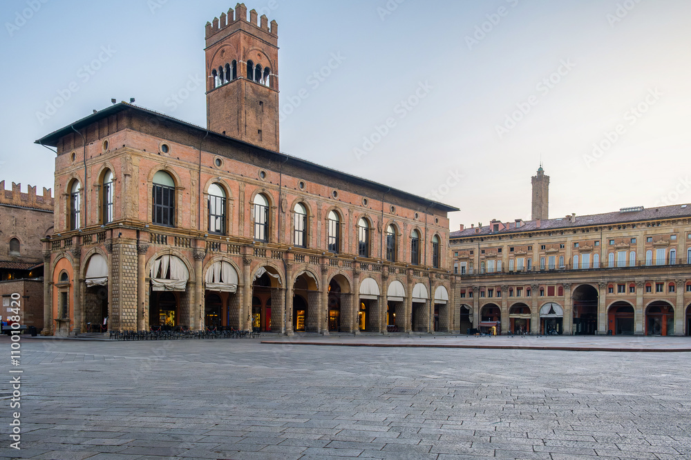 Fototapeta premium Piazza Maggiore in Bologna old town, Emilia Romagna, Italy, featuring historic architecture, arched colonnades, and the iconic Palazzo del Podesta at sunrise with nobody. Travel destination in Europe
