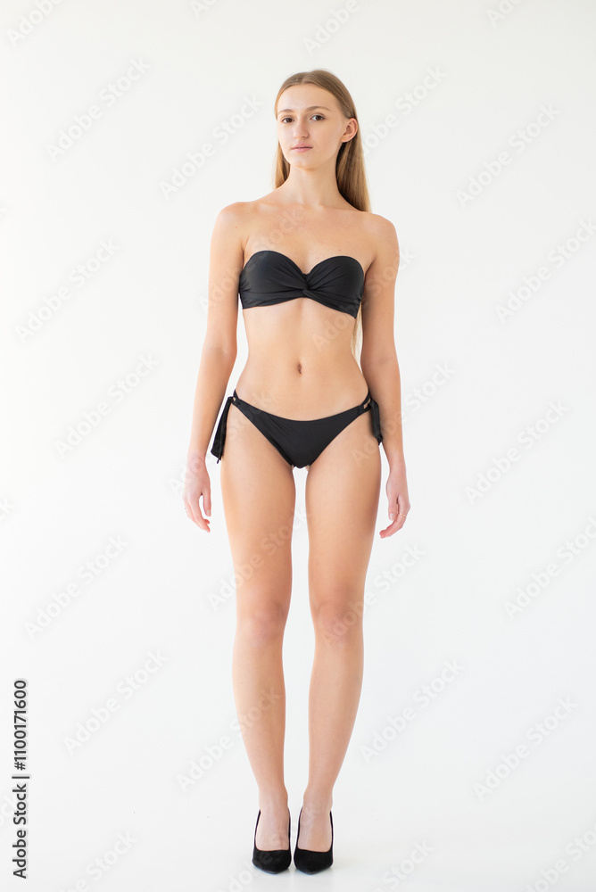 Naklejka premium young woman in black lingerie and underwear posing on grey background. model agency test shoot