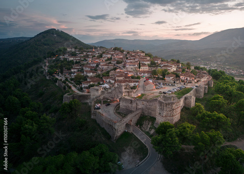 Aerial view of berat castle and old town surrounded by mountains and greenery at sunset, berat, albania. photo