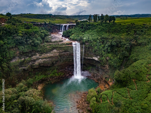 Aerial view of a breathtaking waterfall cascading through a lush green forest, Skhentalang, India.