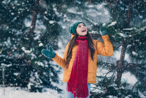 Portrait of attractive cheerful pre-teen girl having fun throwing snow touching spuce eve noel time in forest outdoors photo