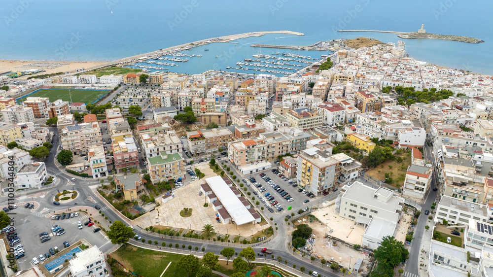 Fototapeta premium Aerial view of the tourist port of Vieste, in the province of Foggia, Puglia, Italy. It is a small marina overlooking the Adriatic Sea. In foreground is the Apulian town.