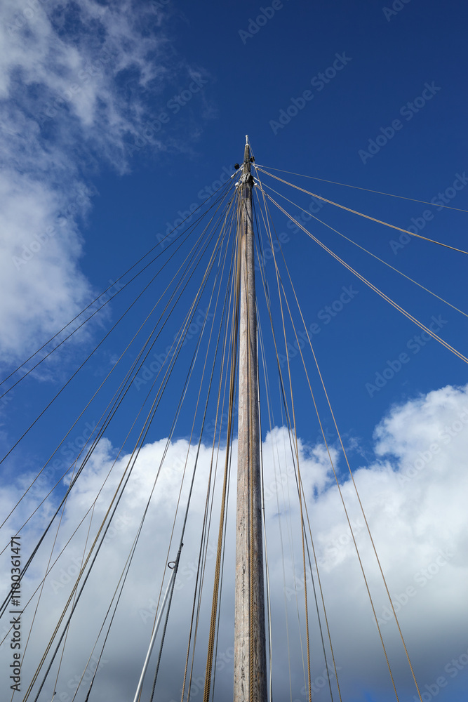 Fototapeta premium The mast without sails goes into the blue sky.