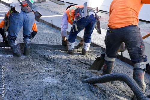 Road crew worker with shovel spreading concrete  photo