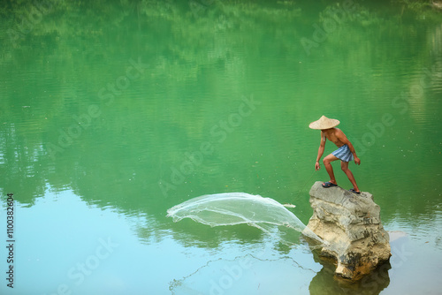 Vietnamese Fisherman Casting Net on Tranquil Green Lake. Traditional Fishing Scene, Ideal for Cultural and Travel concepts.  photo