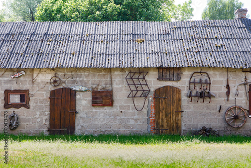 Old village building with decorative farm tools on the wall photo