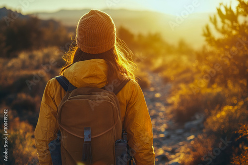 Young female adventurer hiking at sunset in mountain landscape