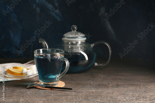 Cup of butterfly pea flower tea and teapot on grunge background photo