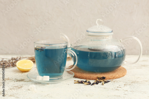 Cup of butterfly pea flower tea and teapot on grunge background photo