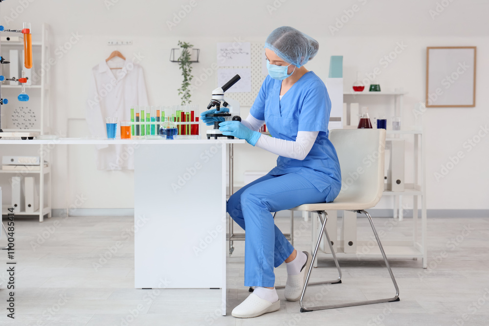 Obraz premium Female chemist with microscope sitting at table in laboratory