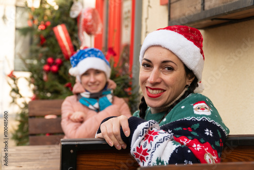 woman and teenager in New Year's hats, New Year's sweater, mother and daughter sitting in a restaurant, happy family, New Year's decor, Christmas, New Year photo