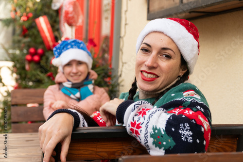 woman and teenager in New Year's hats, New Year's sweater, mother and daughter sitting in a restaurant, happy family, New Year's decor, Christmas, New Year photo