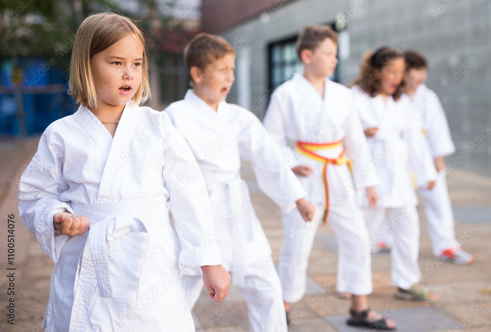 Young children in kimono perform techniques karate on a city street Young children in kimono perform techniques karate on a city street